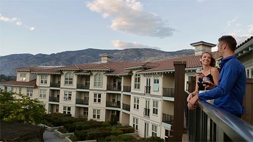 couple on balcony drinking wine with view of mountains